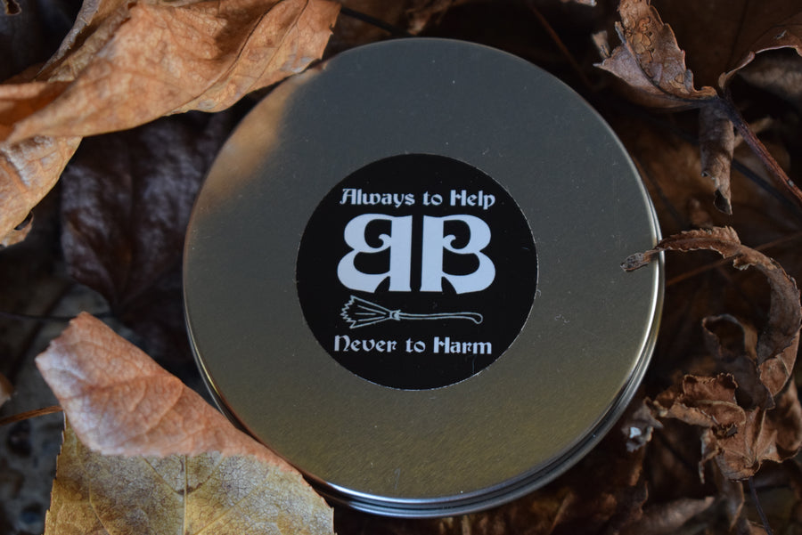 A tin of sand nestled in autumn leaves with label on lid saying always to help never to harm BB on the lid