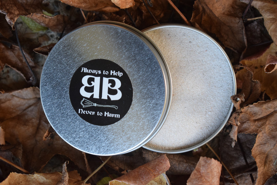 A tin of sand half open nestled in autumn leaves with label on lid saying always to help never to harm BB on the lid