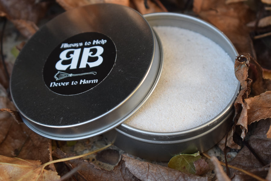 A tin of sand half open nestled in autumn leaves with label on lid saying always to help never to harm BB on the lid