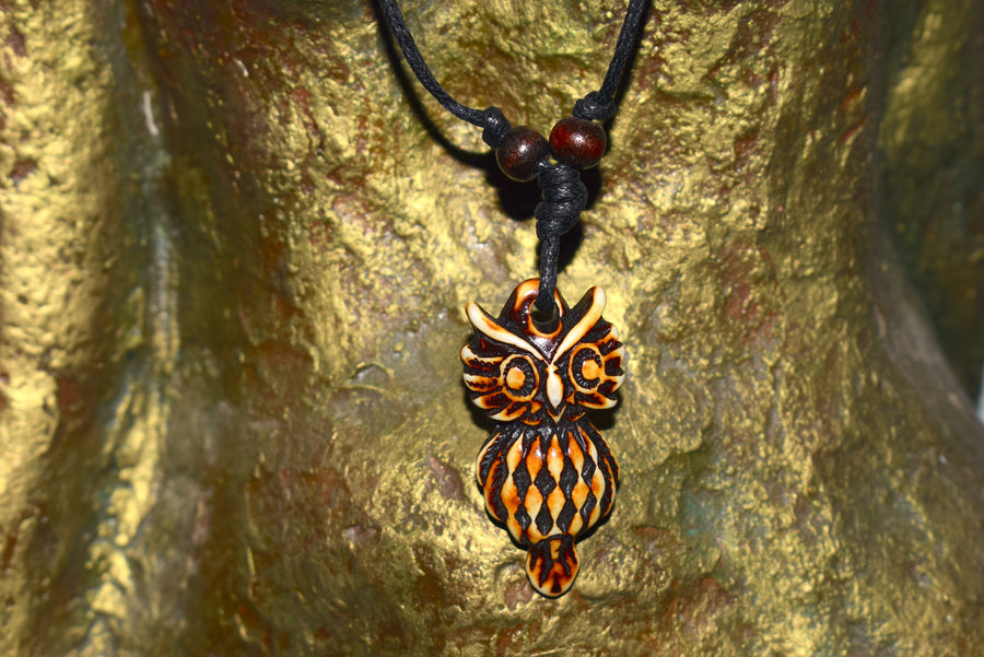 Brown resin owl pendant on black cord with two beads on torso of bronze goddess statue