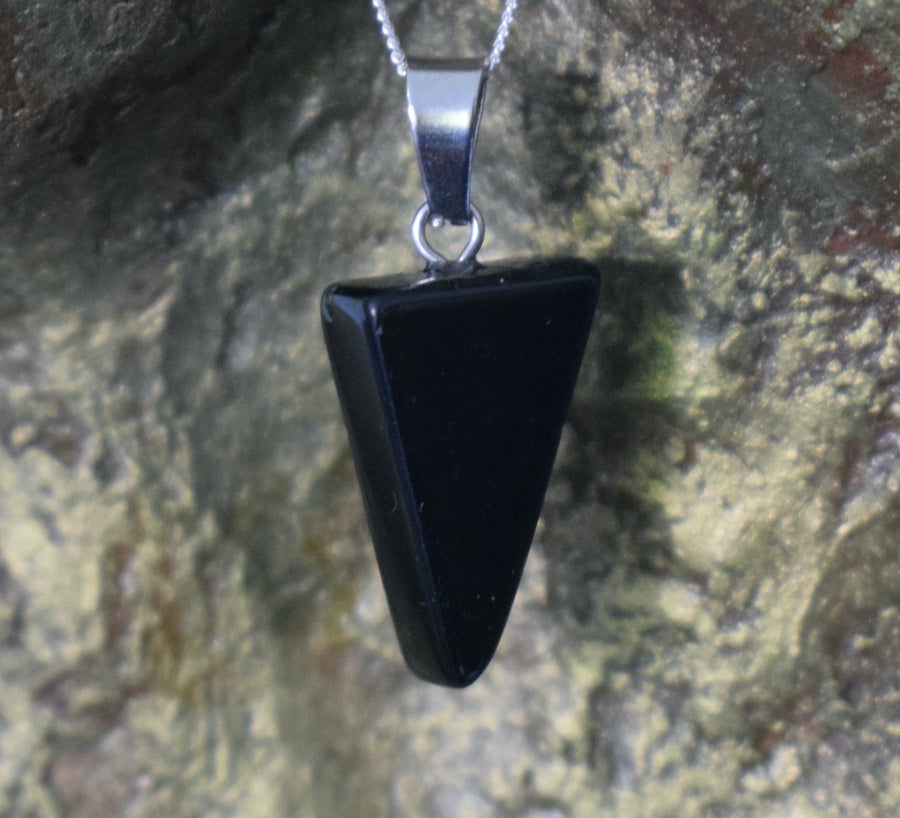 A black tourmaline crystal inverted triangle necklace on a sterling silver chain hanging on the neck of a bronze sculpture