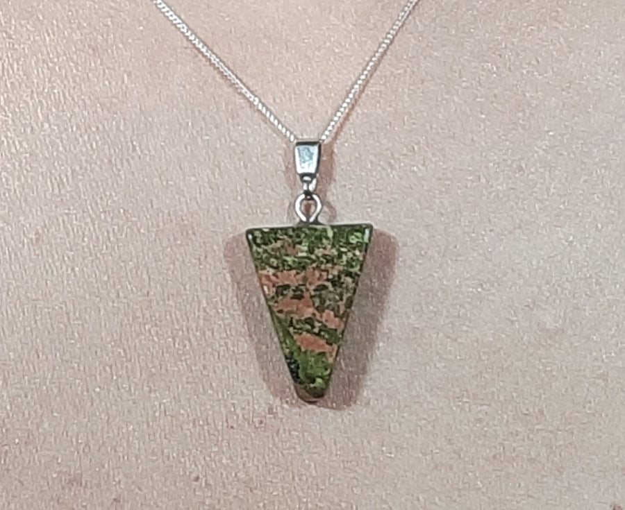 A unakite crystal inverted triangle necklace on a sterling silver chain hanging on the neck of a person