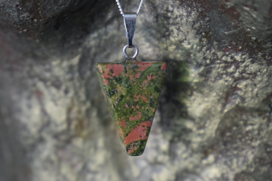 A unakite crystal inverted triangle necklace on a sterling silver chain hanging on the neck of a bronze sculpture