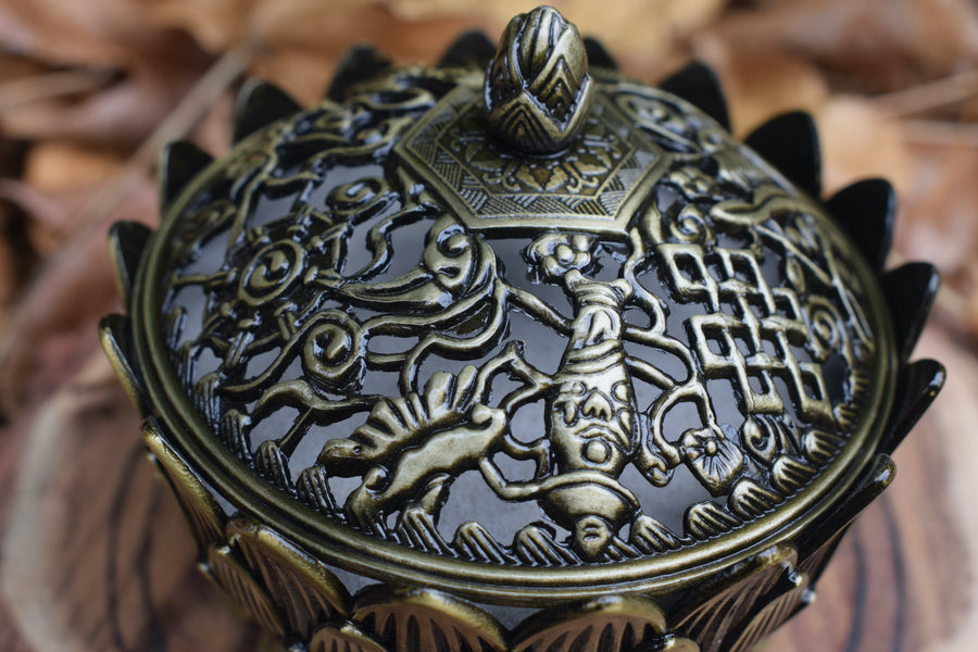 An ornate metal lotus trinket box with a lid 