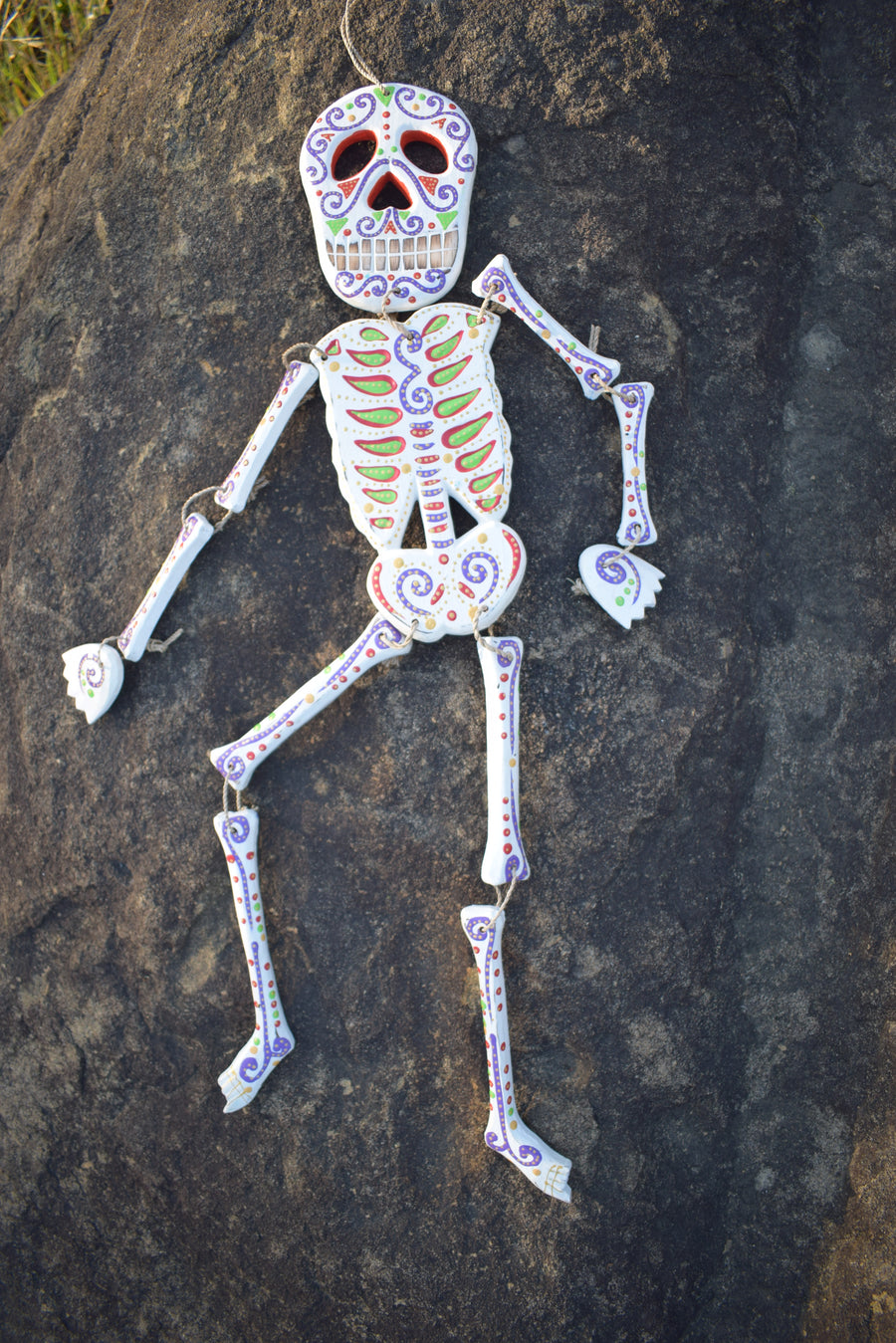 A colourful calaca Day of the Dead spirit medicine rattle resting on a rock