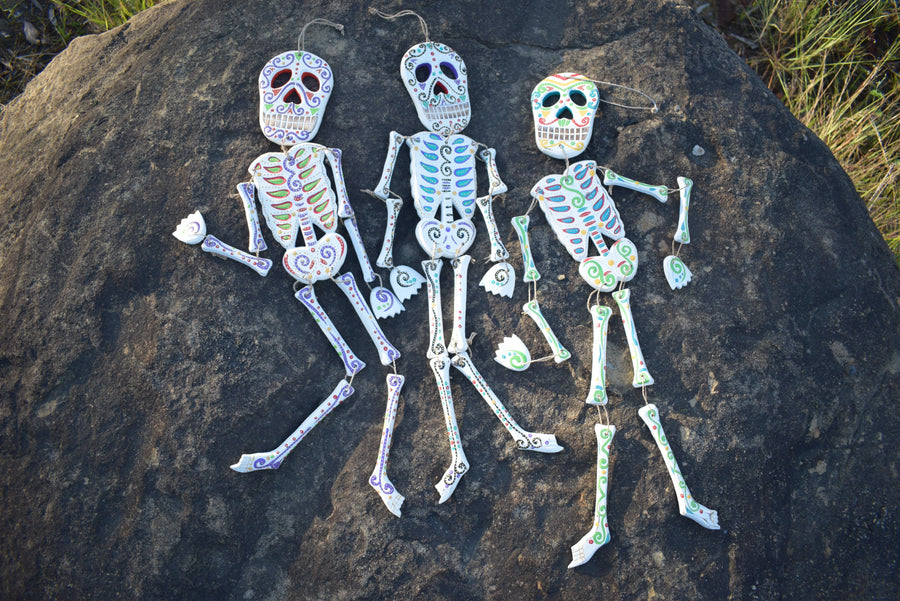 Three colourful calaca Day of the Dead spirit medicine rattles resting on a rock
