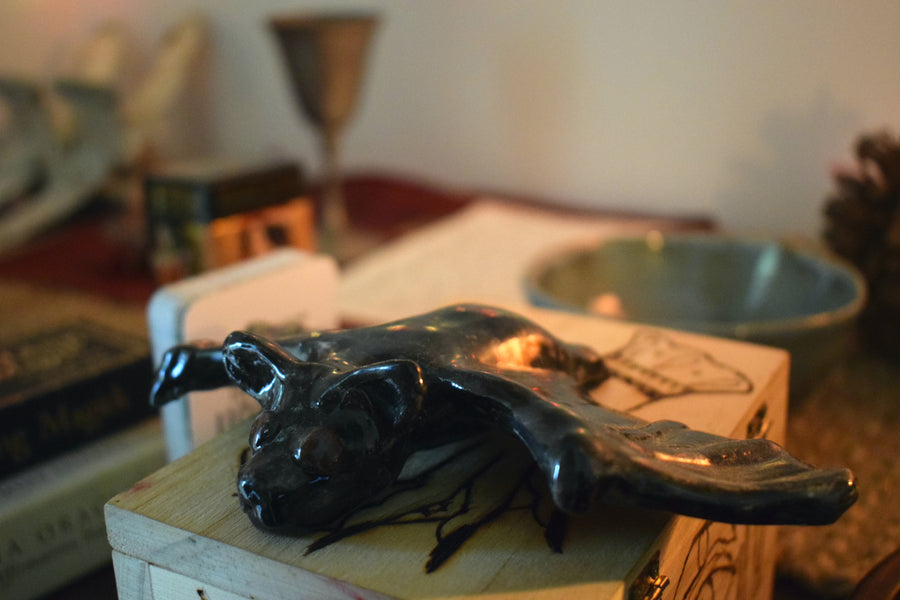 A handmade ceramic flying fox bat resting on an wooden box 
