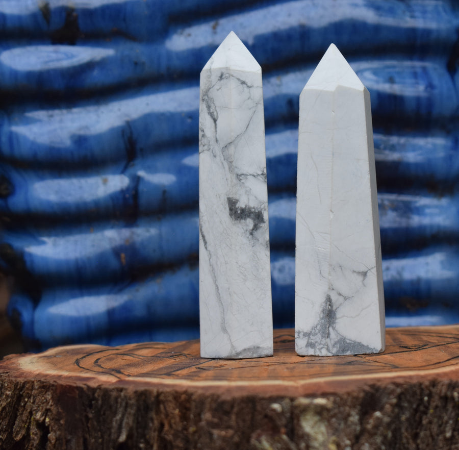Two white howlite obelisk crystal points resting on a pentagram wooden disk.