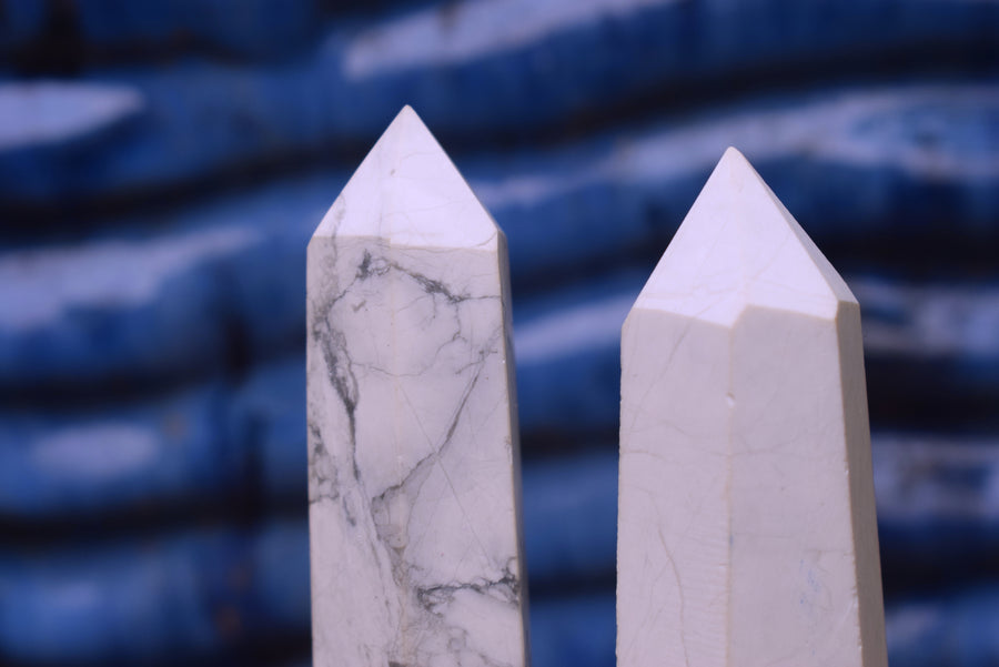 Two white howlite obelisk crystal points with a blue background