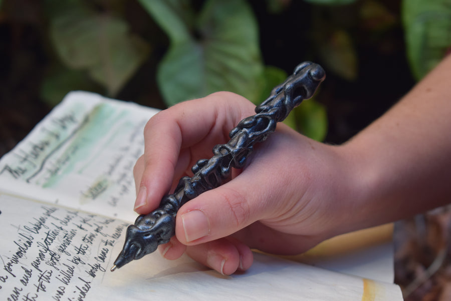 Hand writing a spell with a black handcrafted pen in a grimoire