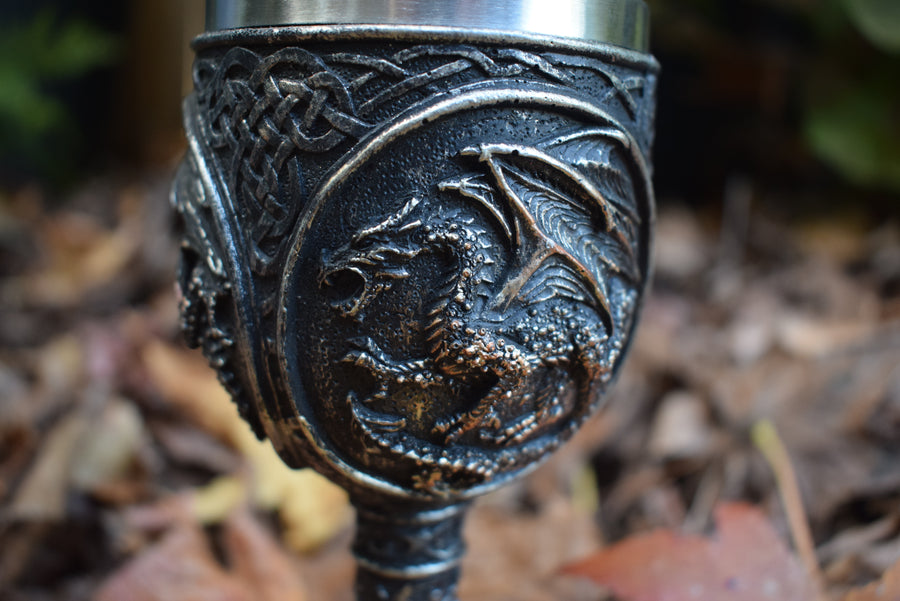 A goblet with a 3d black dragon rests on a bed of autumn leaves