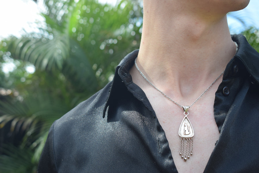 Neck of person wearing black shirt with sterling silver cat pendant with fringing necklace