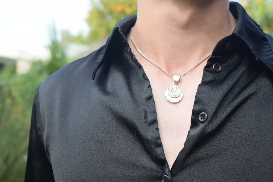 Chest with open buttons revealing a sterling silver spiral and runic necklace and chain