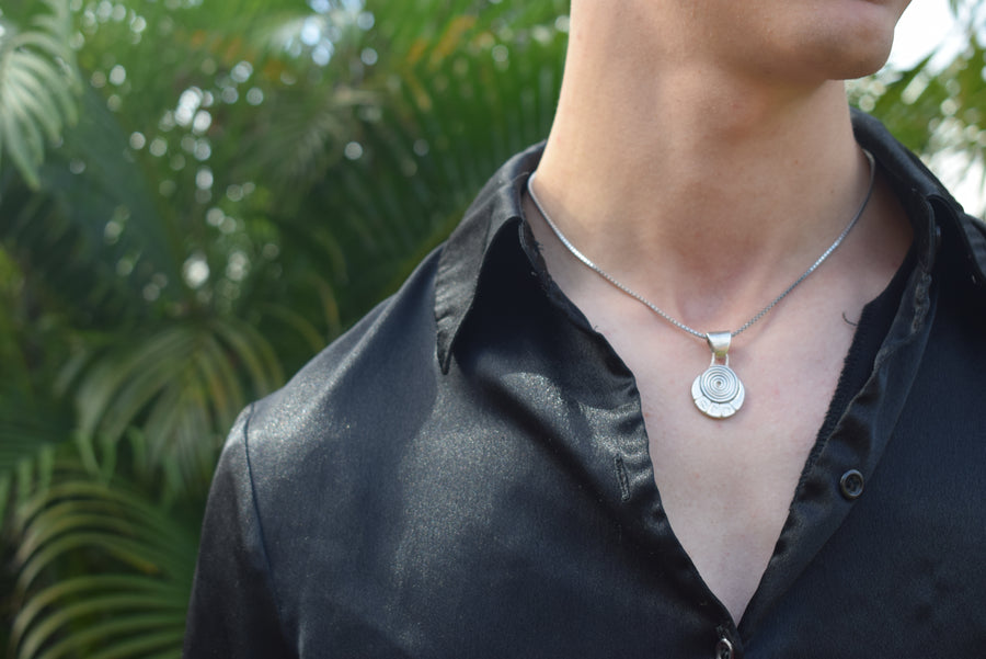 Upper body of a person wearing a sterling silver spiral and runic necklace and chain
