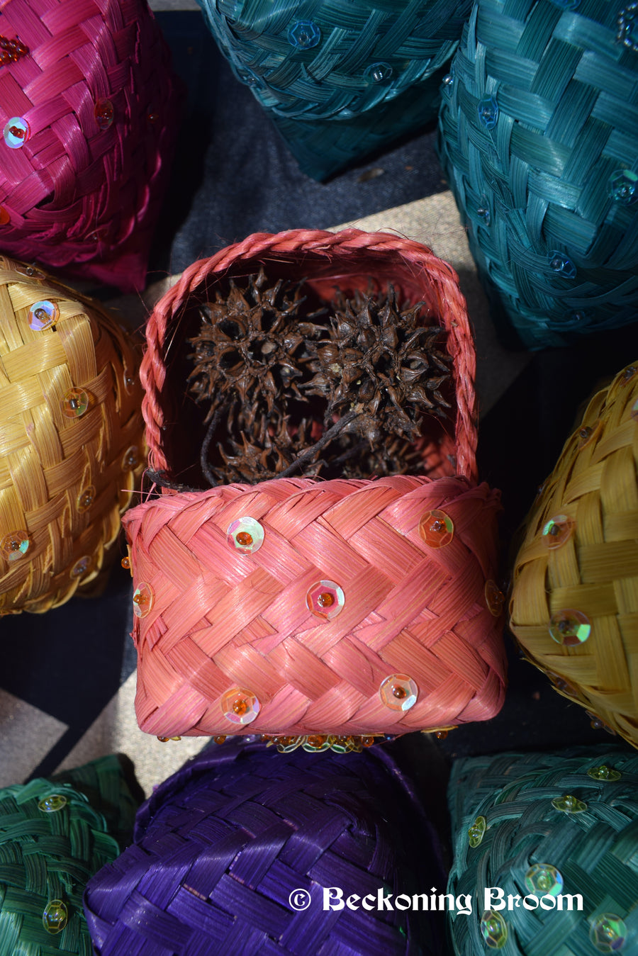 Orange raffia boxes containing witches burrs resting on a pentagram altar cloth