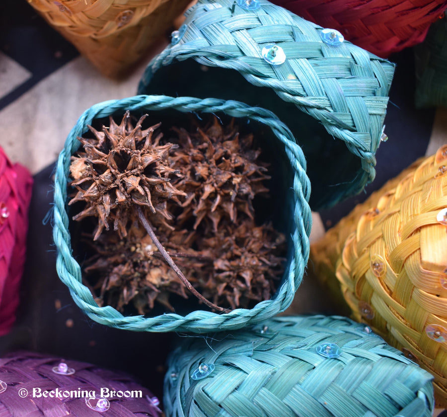 Blue raffia boxes containing witches burrs resting on a pentagram altar cloth