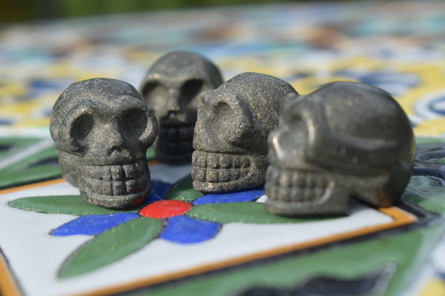Four mini skulls carved from gold pyrite sits on a mosaic.