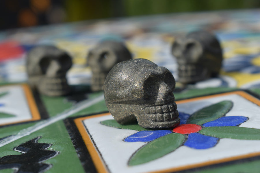 Four mini skulls carved from gold pyrite rest on a mosaic.