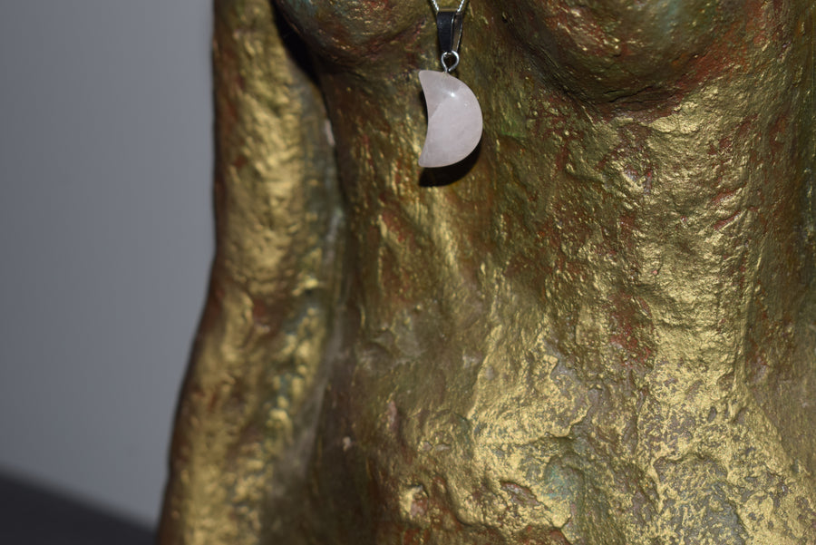 Bronze goddess sculpture wearing rose quartz crescent moon pendant on silver chain