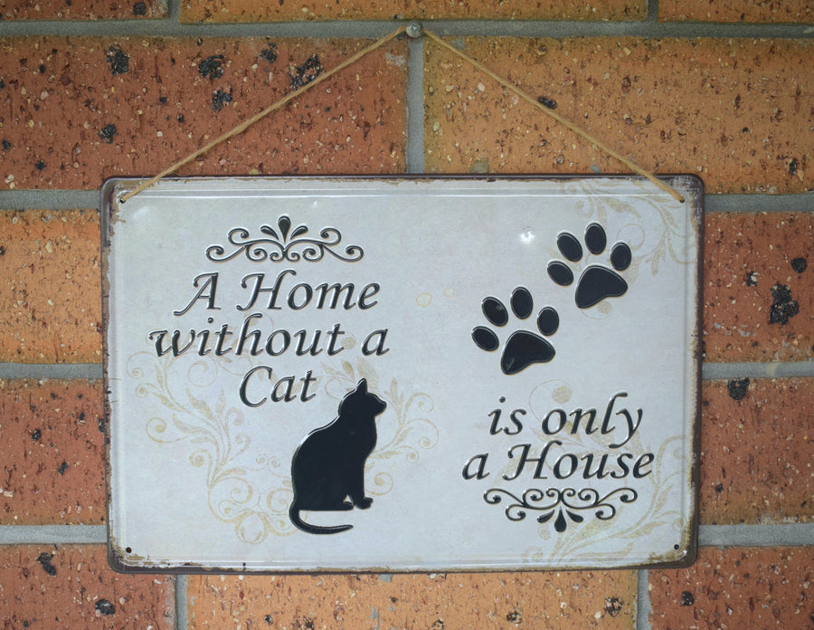 A metal sign with a black cat and two black paw prints saying A Home without a Cat is only a House on it hanging on a brick wall