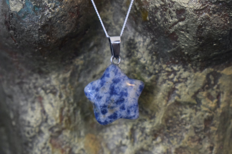 A sodalite crystal crescent moon necklace on a sterling silver chain hanging on the neck of a bronze sculpture