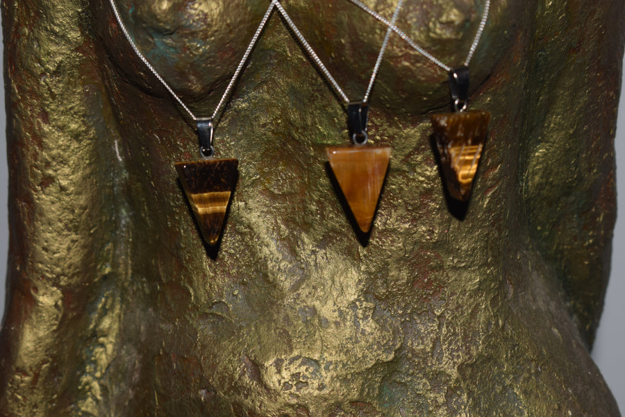 Three tiger's eye triangle pendants on silver chains worn by bronze torso sculpture