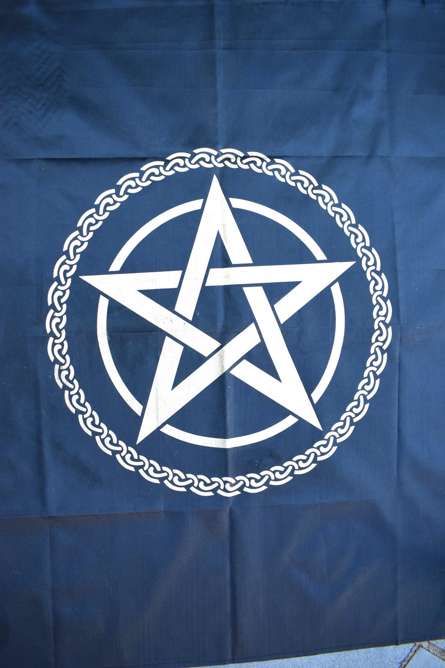A black satin altar cloth or witches flag with gold pentagram pentacle in the middle encircled by a celtic knot