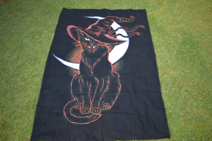 Black hand painted fabric throw with cat wearing witches hat outlined in pink and orange with white crescent moon in background