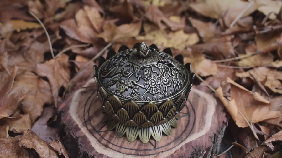 A hand lifting a metal lotus trinket box lid with autumn leaves in the background