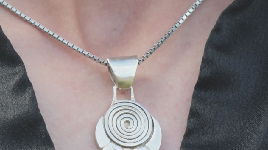 Chest with a hand touching sterling silver spiral and runic necklace and chain