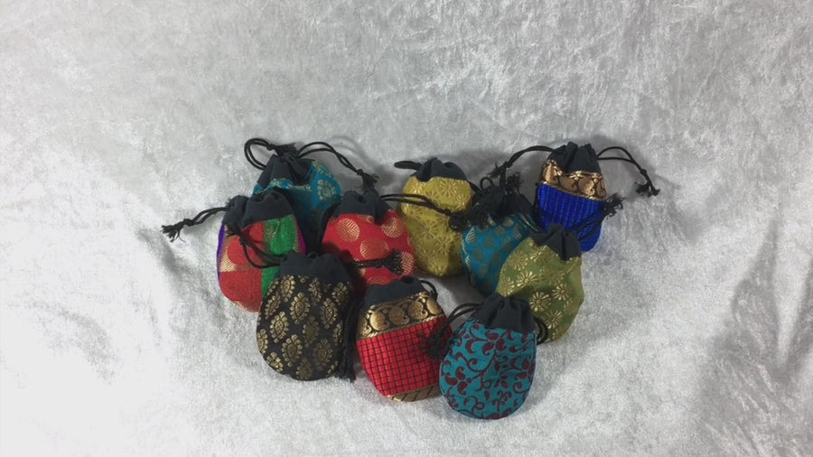 Ten different coloured fabric drawstring lucky dip pouches with a hand picking them up