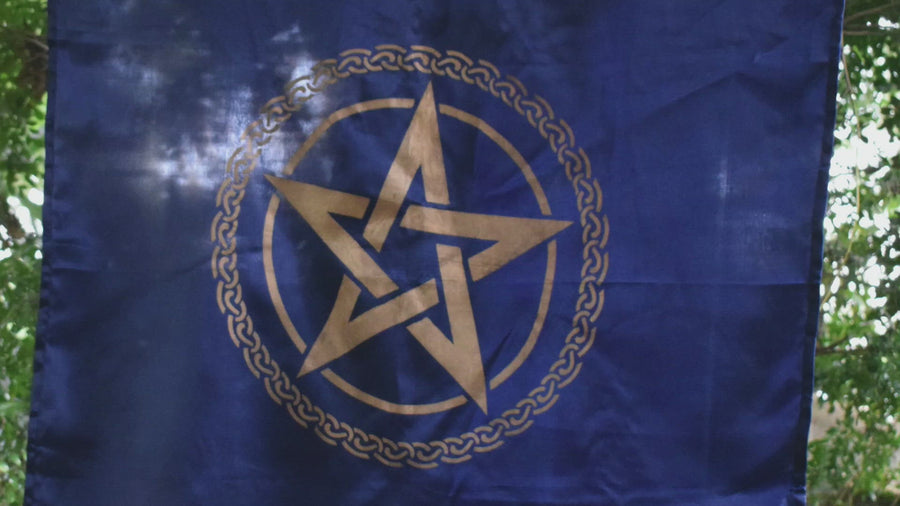 Person unrolling and holding a large royal blue altar cloth, witches flag tapestry with gold tree of life celtic knot encircling a gold pentagram pentacle