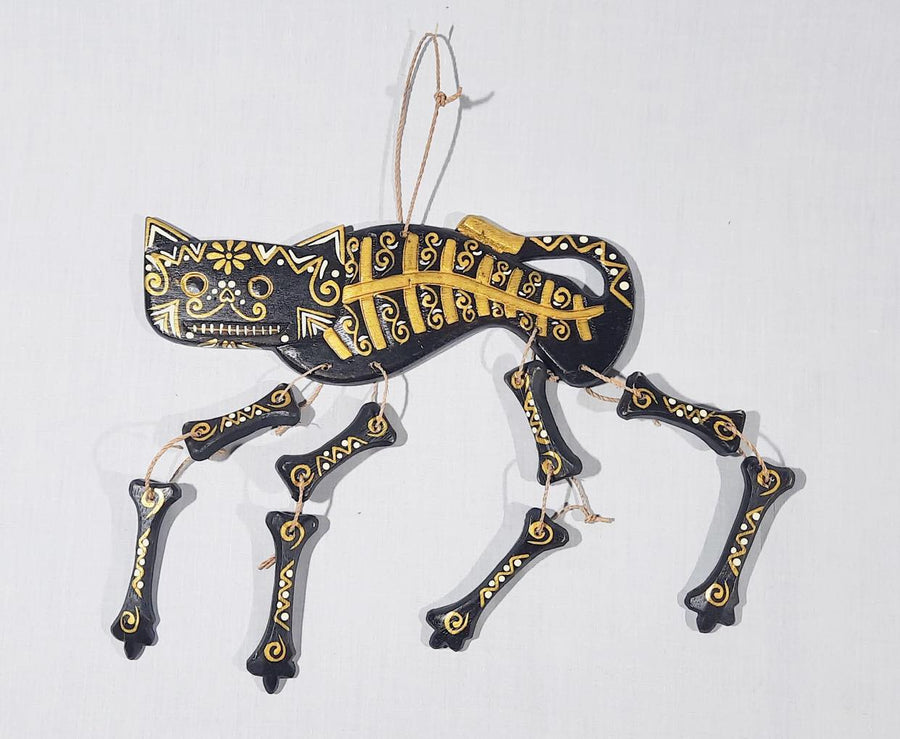 A black cat skeleton calavera spirit rattle with gold and white lying on a white background 