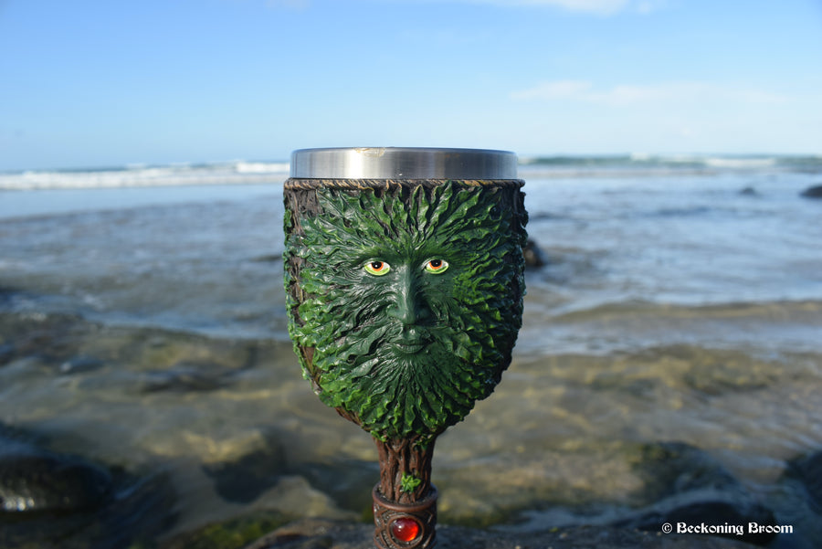 A goblet depicting the green man sits on a rock with the ocean in the background.