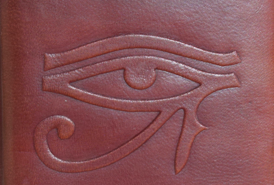 A leather-bound book of shadows with an eye of horus embossed on the cover 