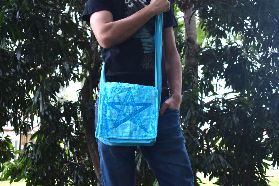 Person wearing light blue shoulder bag with pentagram on the front