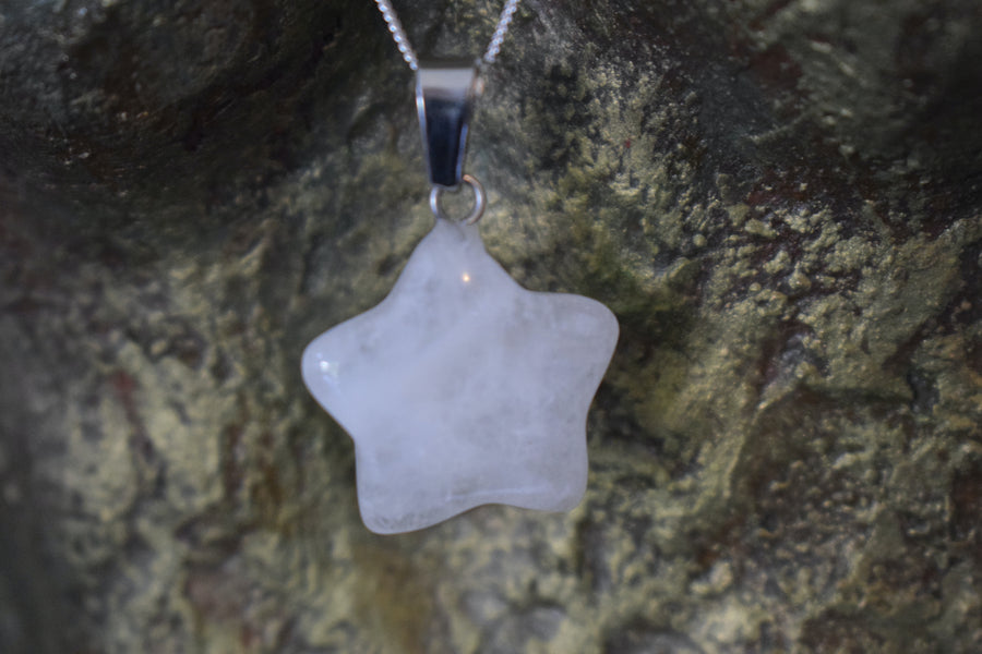 A rose quartz crystal pentagram star necklace on a sterling silver chain hanging on the neck of a bronze sculpture