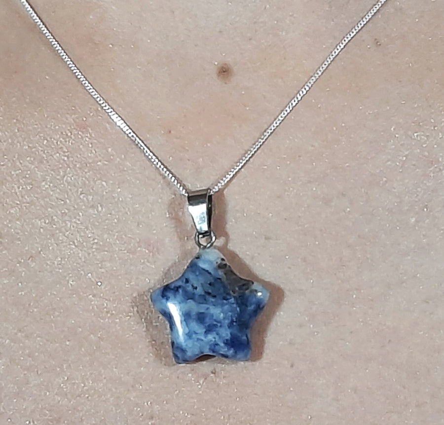 A sodalite crystal crescent moon necklace on a sterling silver chain hanging on the neck of a person