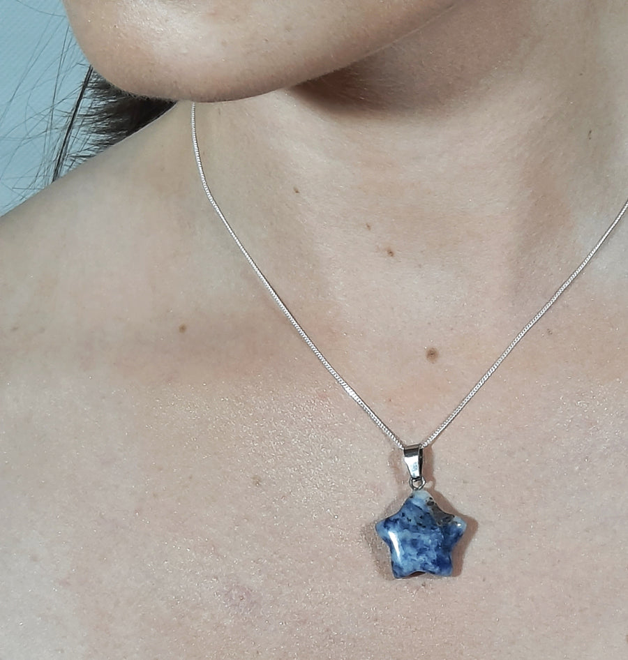 A sodalite crystal crescent moon necklace on a sterling silver chain hanging on the neck of a person