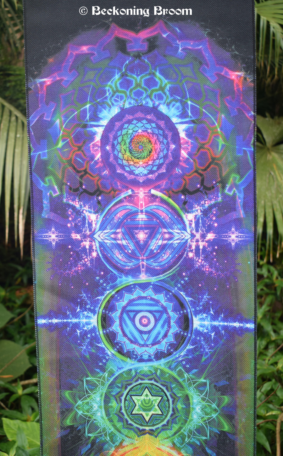 A colourful tapestry depicting chakra points hangs with greenery in the background.