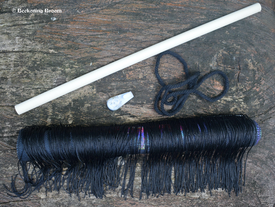 A rolled up tapestry with a piece of dowel, a piece of rope and a hook rest on a piece of timber.